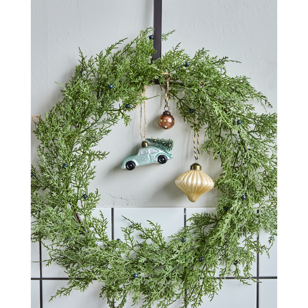 A green pine wreath decorated with three ornaments, including a House Doctor Car Bauble Ornament with Tree 2026, Light Blue & Silver, shaped like a vintage car carrying a tree.
