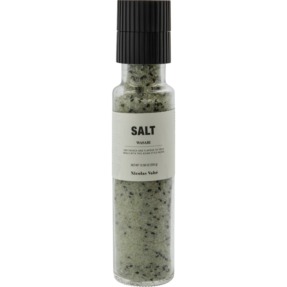 A clear glass grinder labeled “Salt, Wasabi” by Nicolas Vahé contains green and black speckled wasabi salt and black sesame seeds—a striking seasoning for any dish.