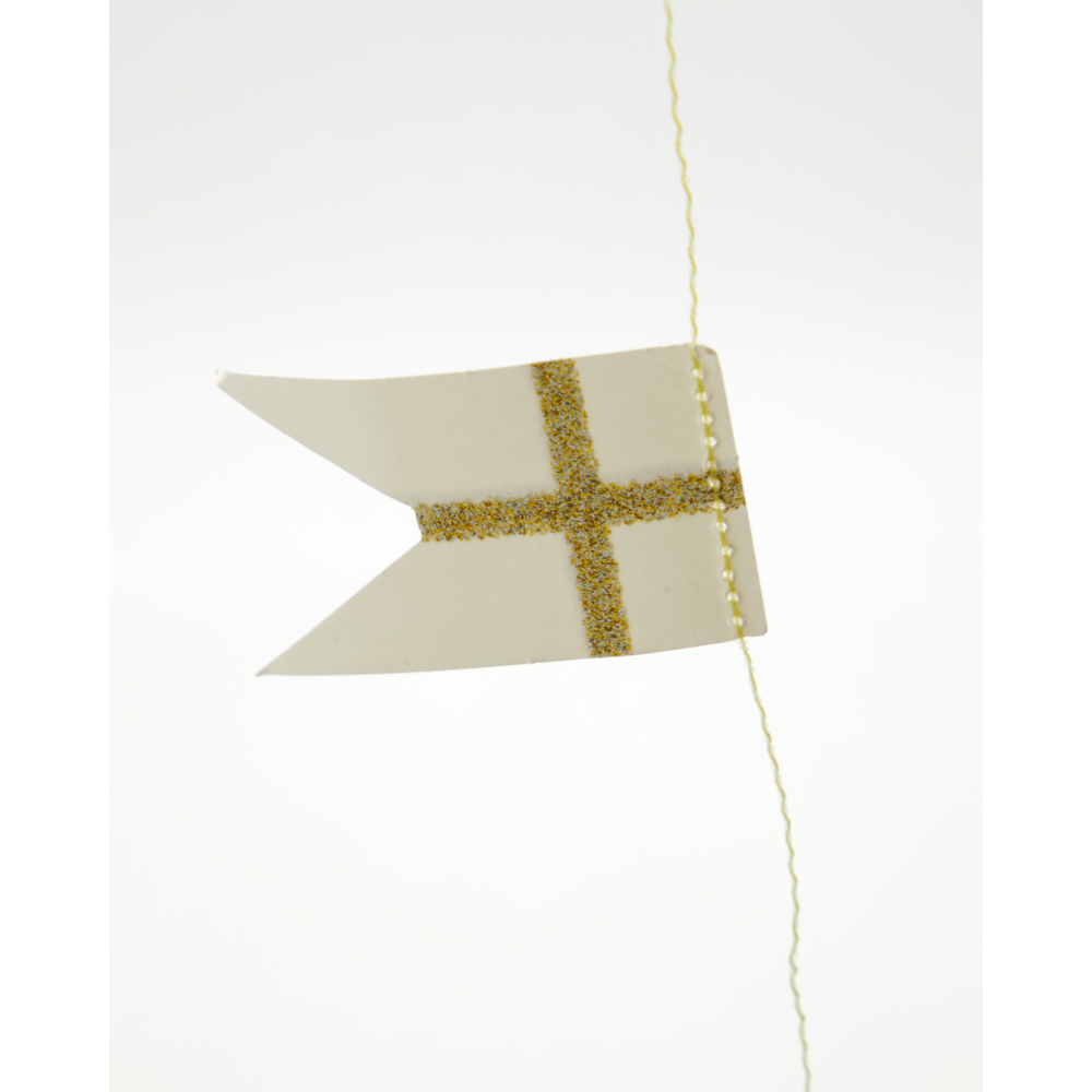 A white swallowtail Garland Flags in White & Champagne with a gold glitter cross, hanging as part of a paper flag garland from a thin string.