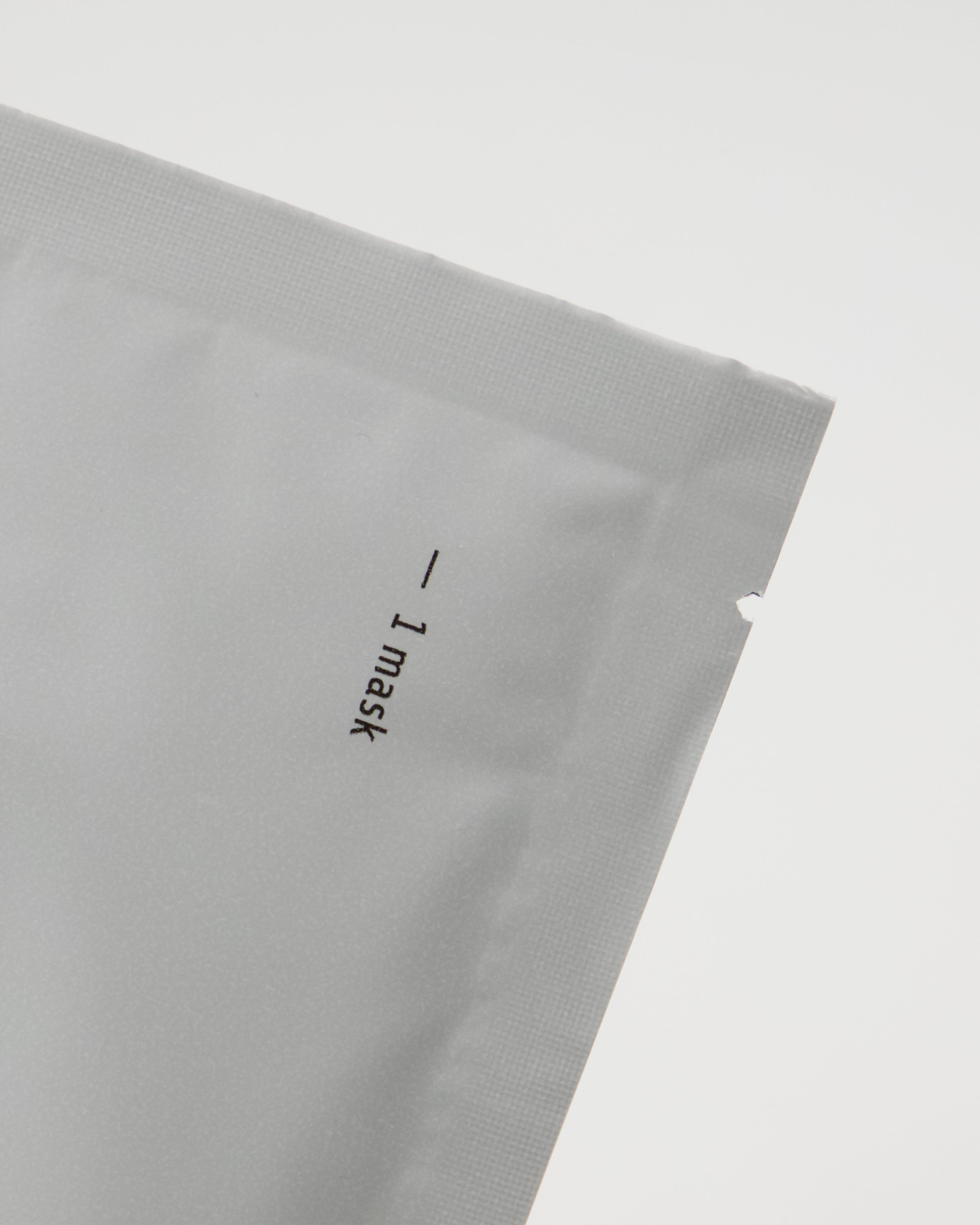A close-up of a silver packet with the text “- 1 mask” printed vertically near the edge, set against a plain white background—an ideal shot for highlighting the Meraki Face Mask, Collagen, designed to boost skin elasticity.