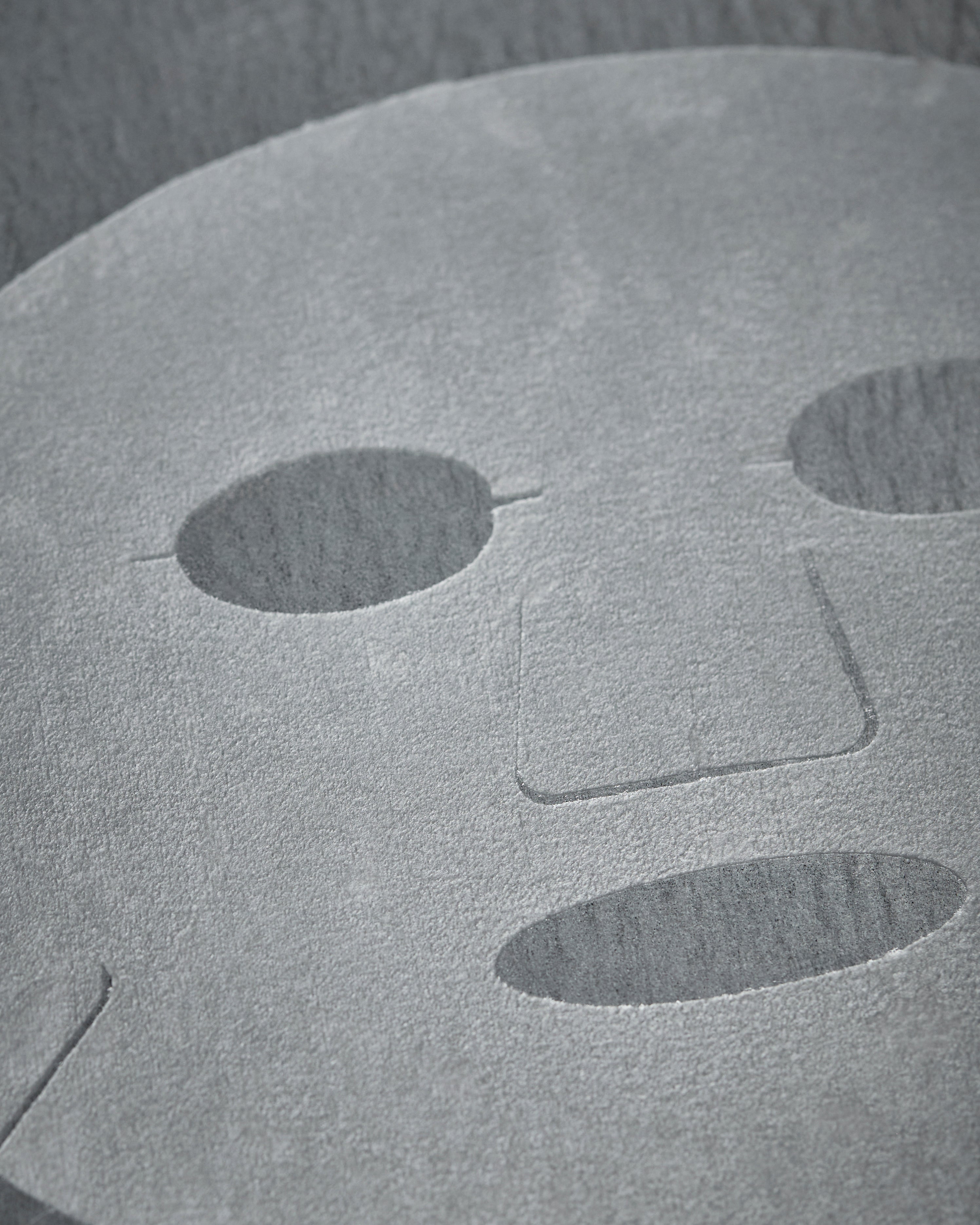 A close-up of the Meraki Face Mask, Collagen, infused with marine collagen to support skin elasticity, featuring cutouts for the eyes, nose, and mouth as it lies flat on a textured surface.