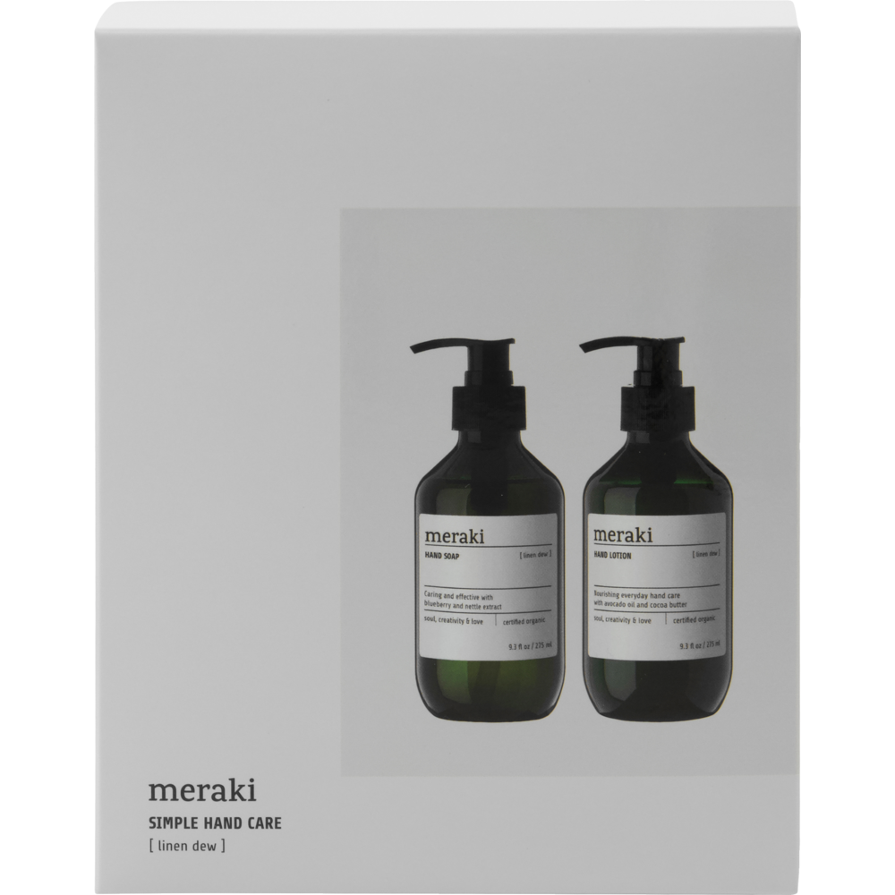 A white box featuring images of two dark pump bottles contains the Meraki Giftbox Linen Dew Organic Hand Soap and Hand Lotion. The black text labels on the bottles describe each Meraki hand care product.