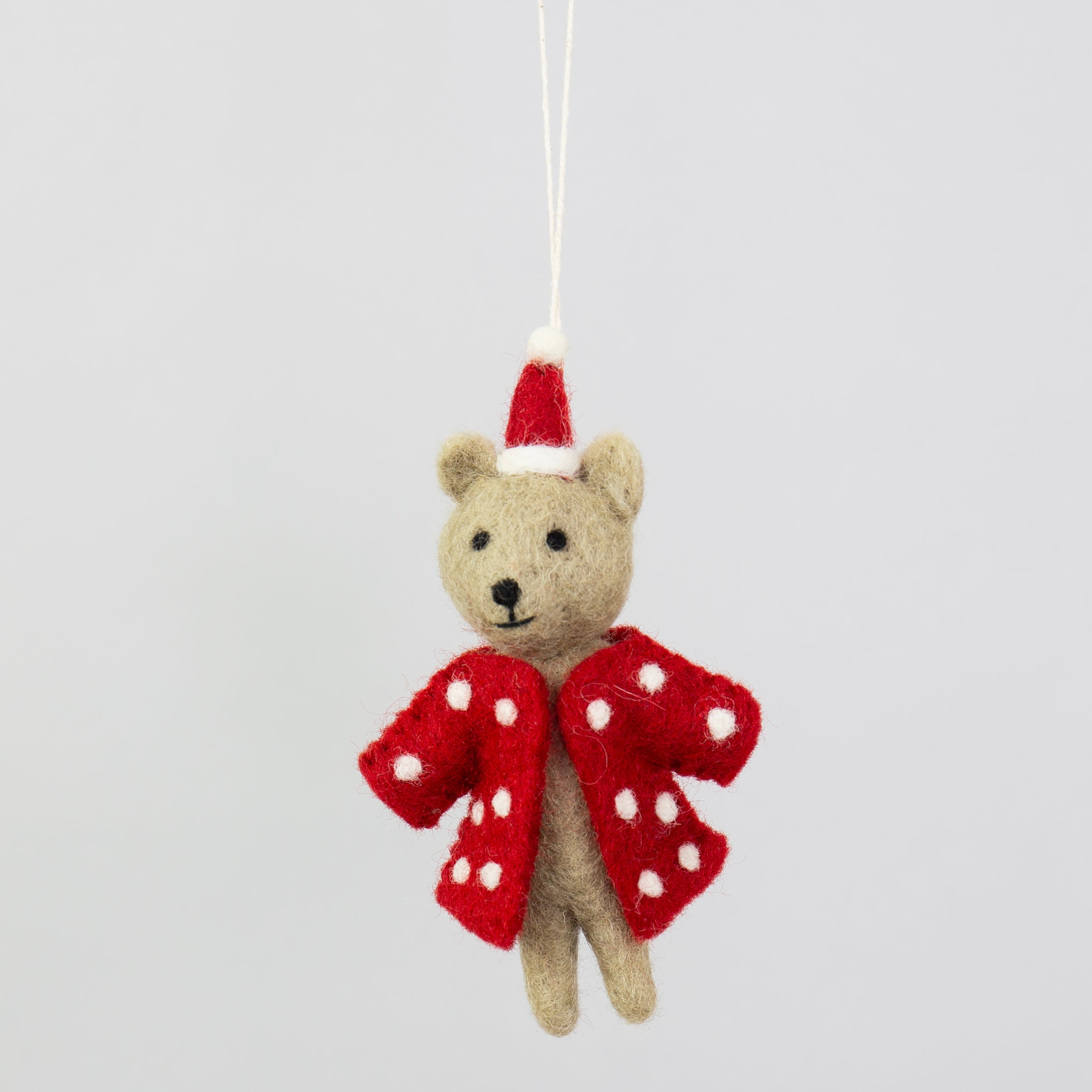 The Wool Bear w. Dotted Red Coat & Christmas Hat from A World of Craft is a charming fair trade wool Christmas ornament, featuring a felt bear in a polka dot coat and Santa hat, perfect for holiday decorating.