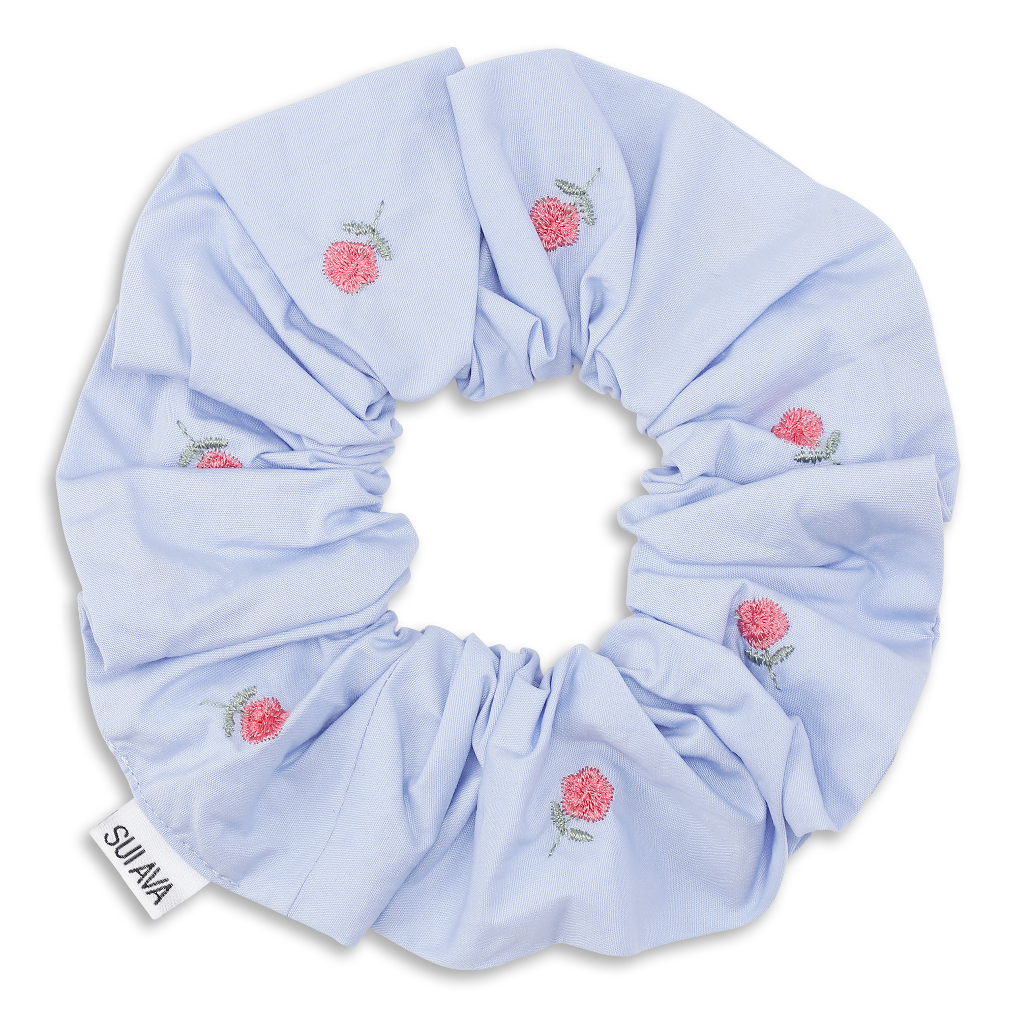 The Bobbie Scrunchie in Light Blue by Sui Ava offers gentle hold and features pink embroidered flowers with green leaves, plus a white Sui Ava tag on the edge for a charming floral touch.