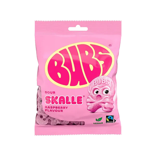 A 90g pink packet of Deli Bubs Sour Raspberry Mix Swedish Candy Skulls with a smiling pink skull illustration on the front. Vegan and Fairtrade logos are displayed—ideal for summer treats.
