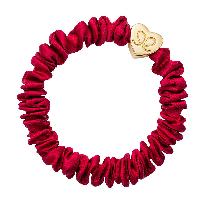 The ByEloise Silk Scrunchie Skinny in Burgundy Red with a gold heart charm is a chic, elegant hair accessory for any occasion.