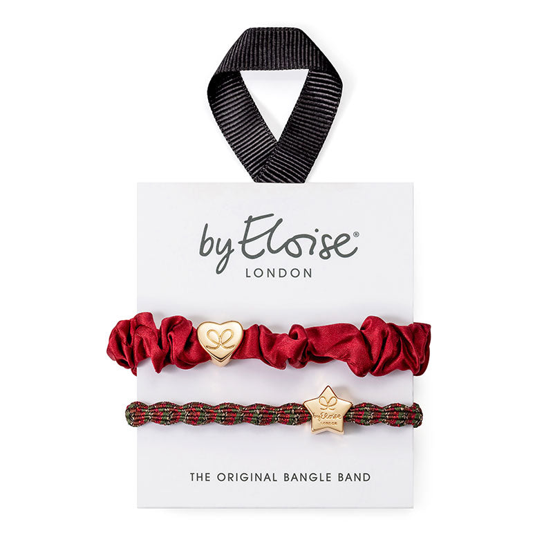 The ByEloise Bangle Band Christmas Highland Set of 2 Hairbands features a red satin band with a heart charm and a plaid band with a star charm, both with gold accents—perfect festive accessories for stylish holiday looks.
