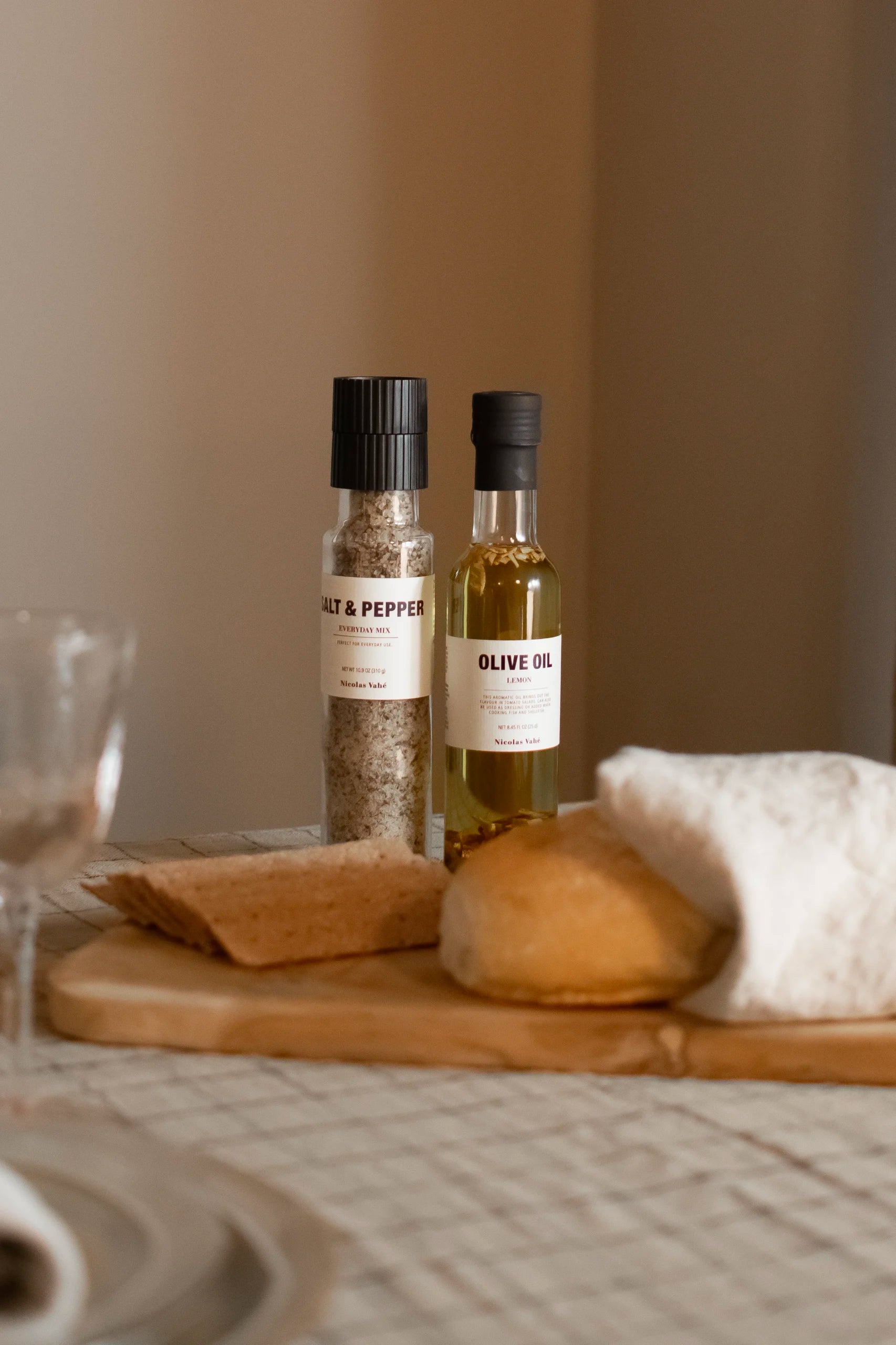 Bottle of olive oil and salt & pepper on a wooden cutting board with a blurred background