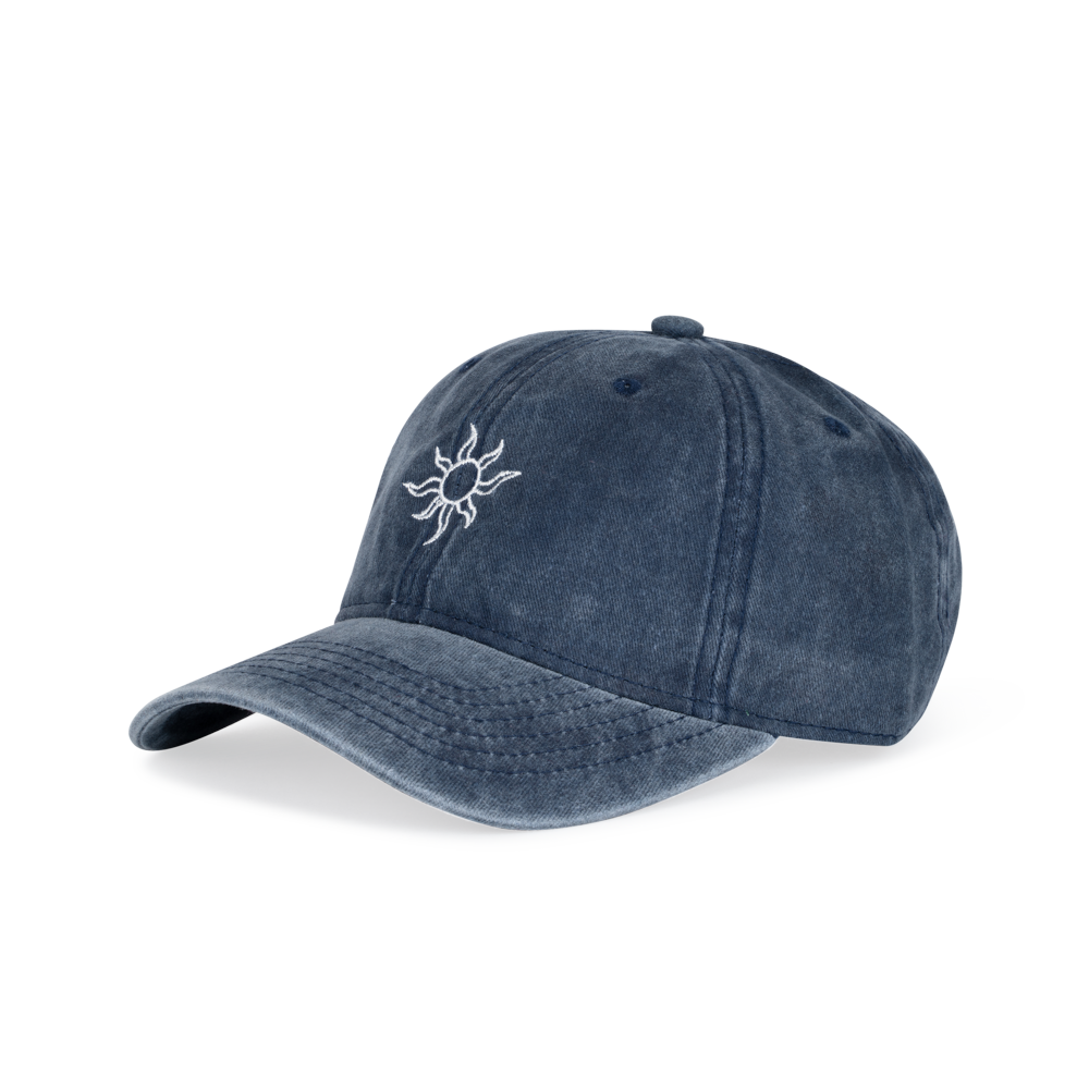 The Sui Ava Everyday Cap in Faded Blue features a white embroidered sun on the front, washed denim construction, and an adjustable strap, shown against a white background.