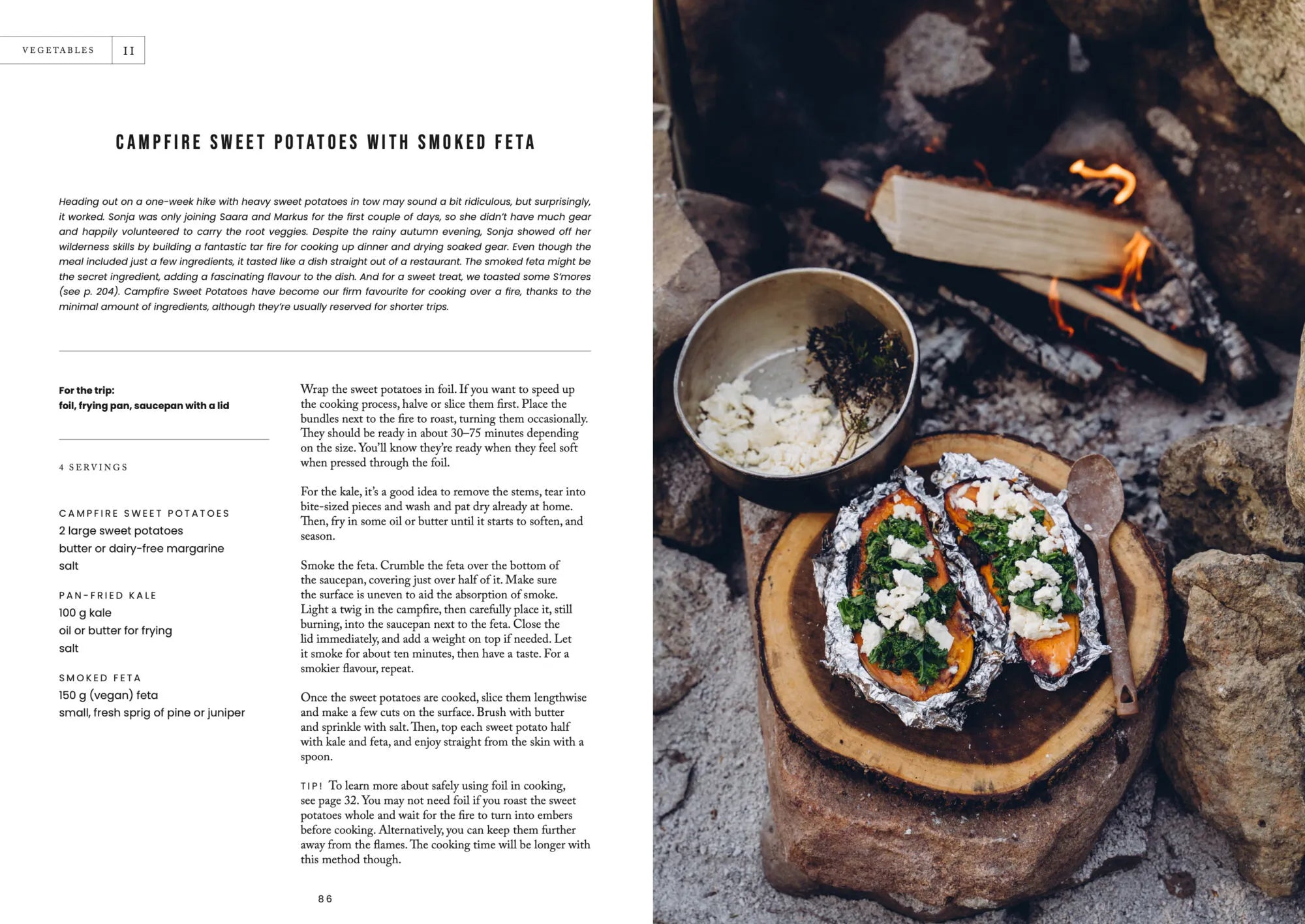 Two sweet potato halves topped with greens and crumbled feta sit on a wooden plate beside a campfire, showcasing an inspiring recipe from Food Over the Campfire – Recipes for Day Hikes and Wilderness Treks by Cozy Publishing. Perfect for adventurous vegetarians, this appetizing dish is accompanied by a bowl of feta and herbs, set next to crackling firewood surrounded by rocks—creating an authentic scene of wilderness cooking.