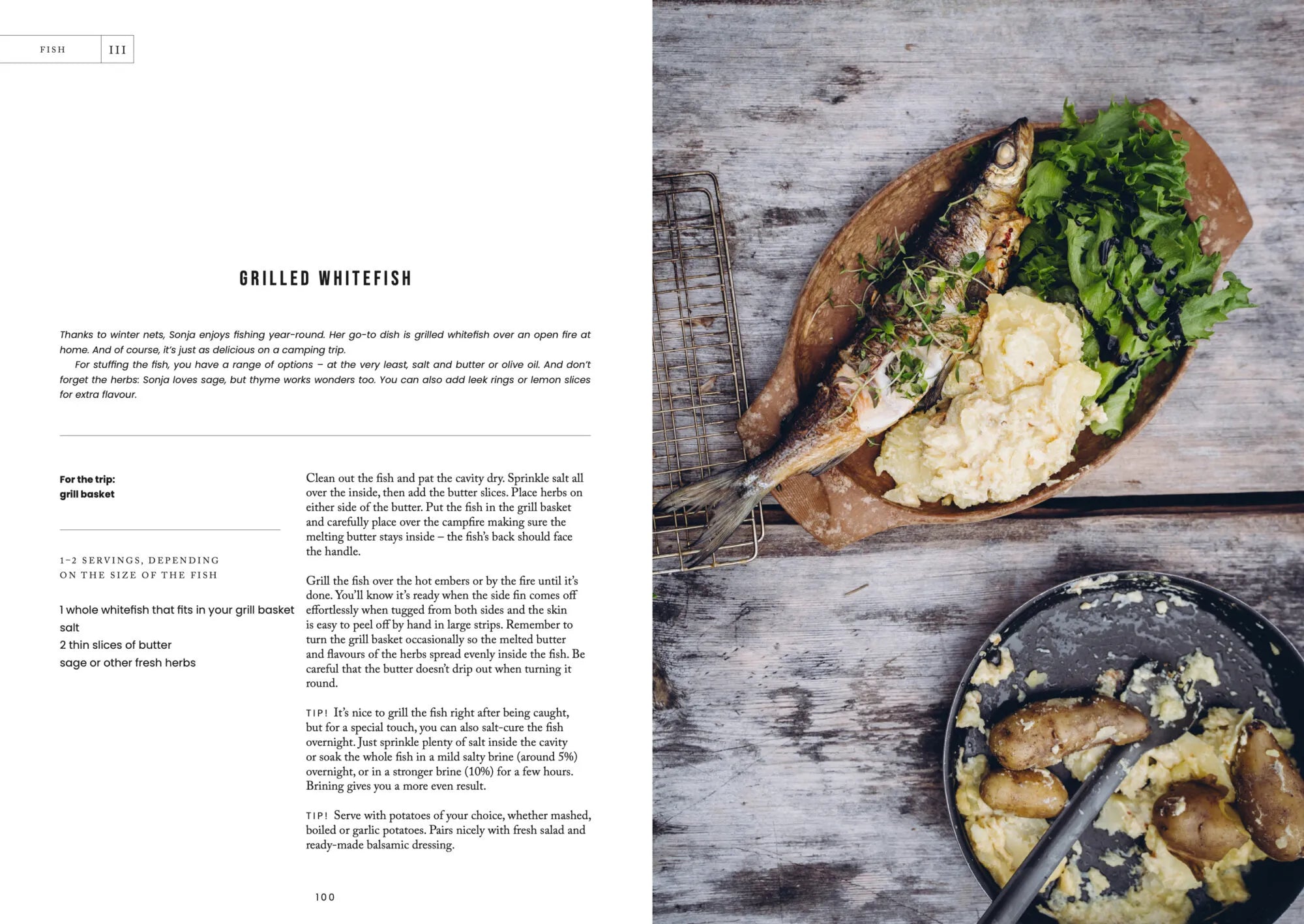 Showcasing the simplicity of wilderness cooking, a whole grilled fish served on a wooden platter with mashed potatoes, lemon wedges, and fresh greens is featured alongside a rustic bowl of mashed potatoes topped with grilled sausages. This hearty campfire meal captures the spirit of outdoor adventure and is inspired by recipes from *Food Over the Campfire – Recipes for Day Hikes and Wilderness Treks* by Cozy Publishing—an ideal guide for those seeking delicious meals in the great outdoors.