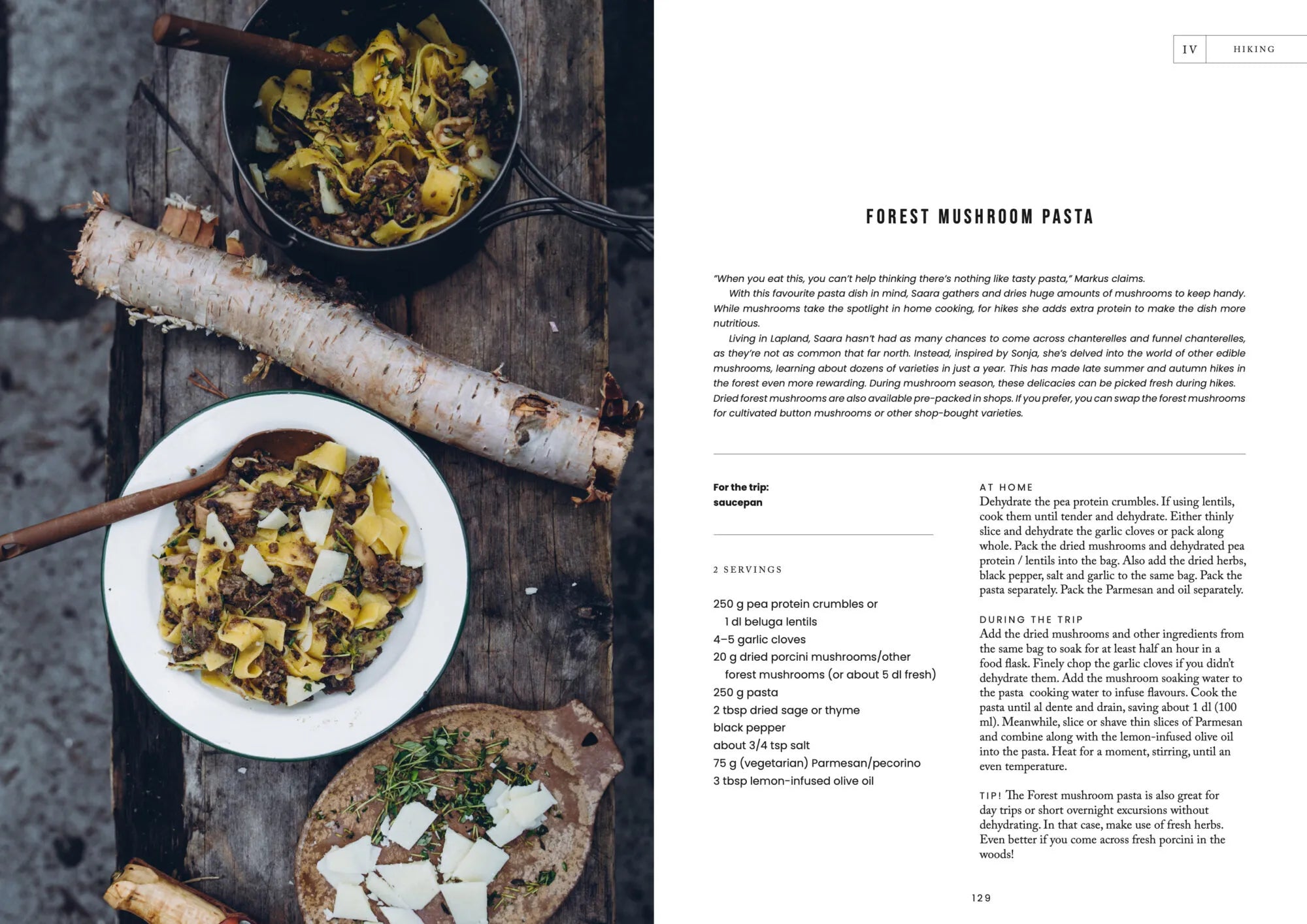 A table set with a skillet and a plate of mushroom and cheese-topped pasta, accompanied by herb bread slices and an open copy of Food Over the Campfire – Recipes for Day Hikes and Wilderness Treks from Cozy Publishing, offers delicious inspiration for anyone interested in vegetarian camping meals or perfecting their wilderness cooking skills.