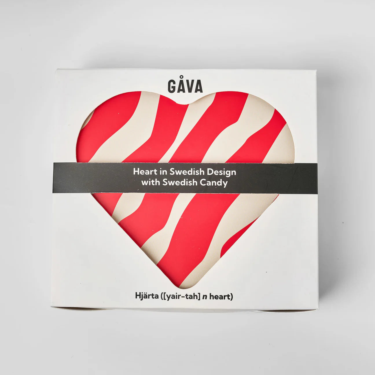 A white box with a heart-shaped window displays red and white Swedish candy. The box reads "Gåva Gifting," "Heart Reusable Tin – Älskar (Love)," and includes a reusable keepsake tin for lasting gifts.