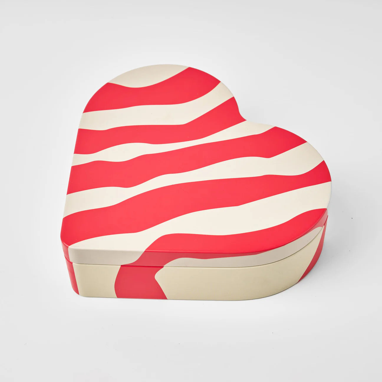 The Heart Reusable Tin - Älskar (Love) by Gåva Gifting features wavy red and cream stripes on a heart-shaped lid—perfect for Swedish candy or as a gift tin—shown on a plain white background.