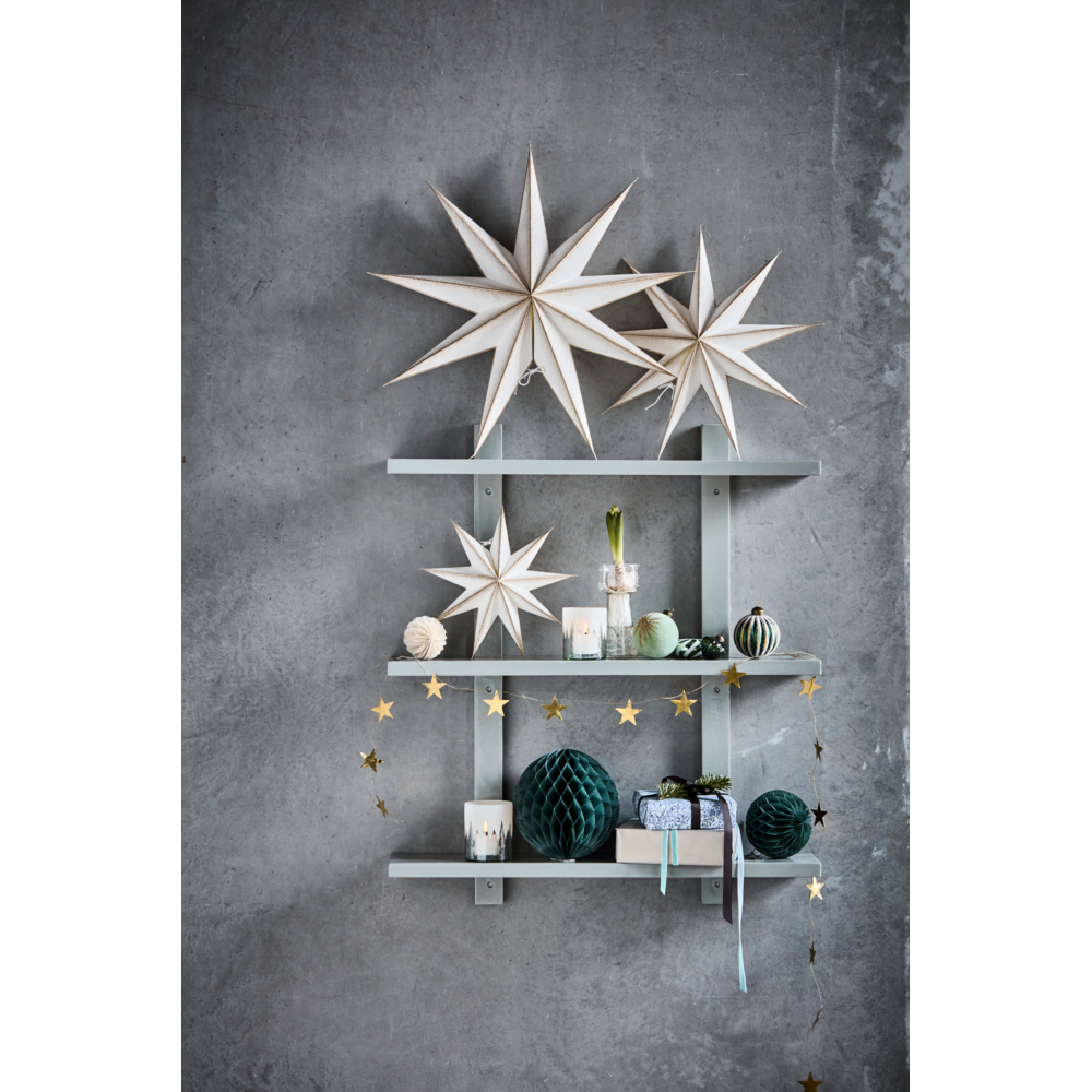 A wall-mounted three-tier shelf decorated with handcrafted stars, honeycomb spheres, candles, and a Garland Stars in Antique Brass, 1.5 m from House Doctor.