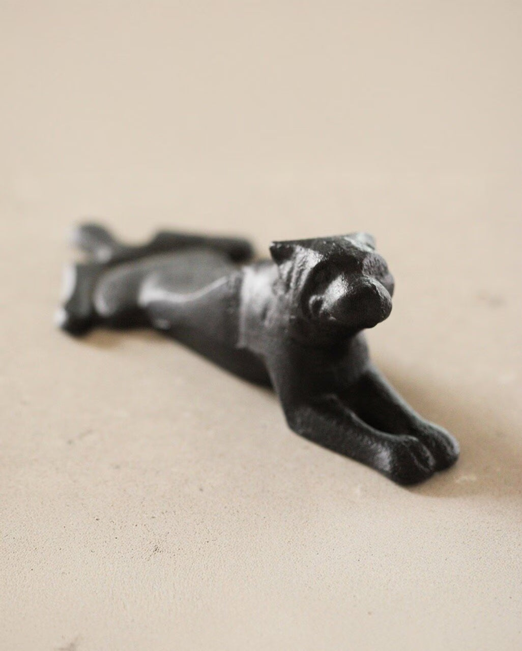 The Strömshaga Door Stopper Dog, crafted from cast iron, is a small black figurine resting on a light-colored surface.