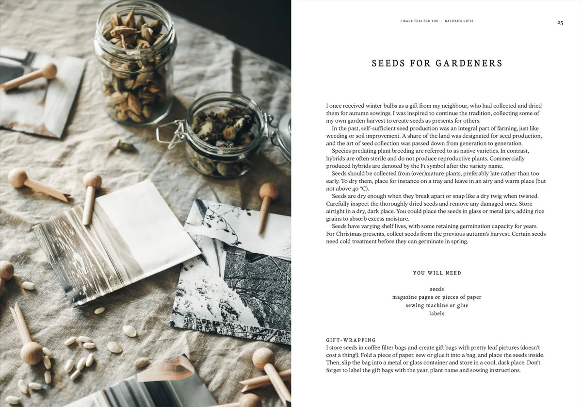 A flat lay featuring seed jars, envelopes, wooden stamps, and magazine pages arranged on a table alongside instructions and a guide from Cozy Publishing’s “I Made This for You – Christmas Gift and Decorations Crafted with Love,” offering creative ideas for packaging seeds as Christmas gifts.