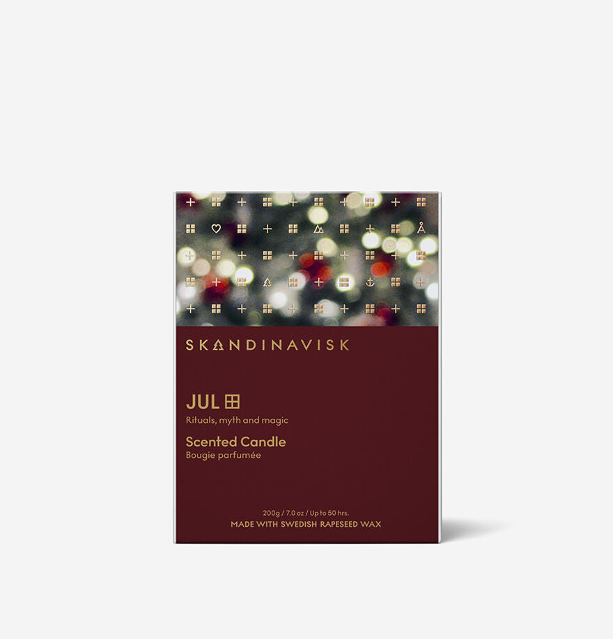 The Skandinavisk Seasonal Jul Scented Candle 50h, 200g comes in a festive box with blurred lights on top and a burgundy base, featuring product and wax details—ideal for capturing the warmth of a Scandinavian Christmas.