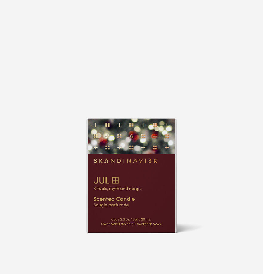 The Skandinavisk Seasonal Jul Scented Candle 65g comes in a festive box with product info on the front, featuring cozy Swedish rapeseed wax for a natural glow.
