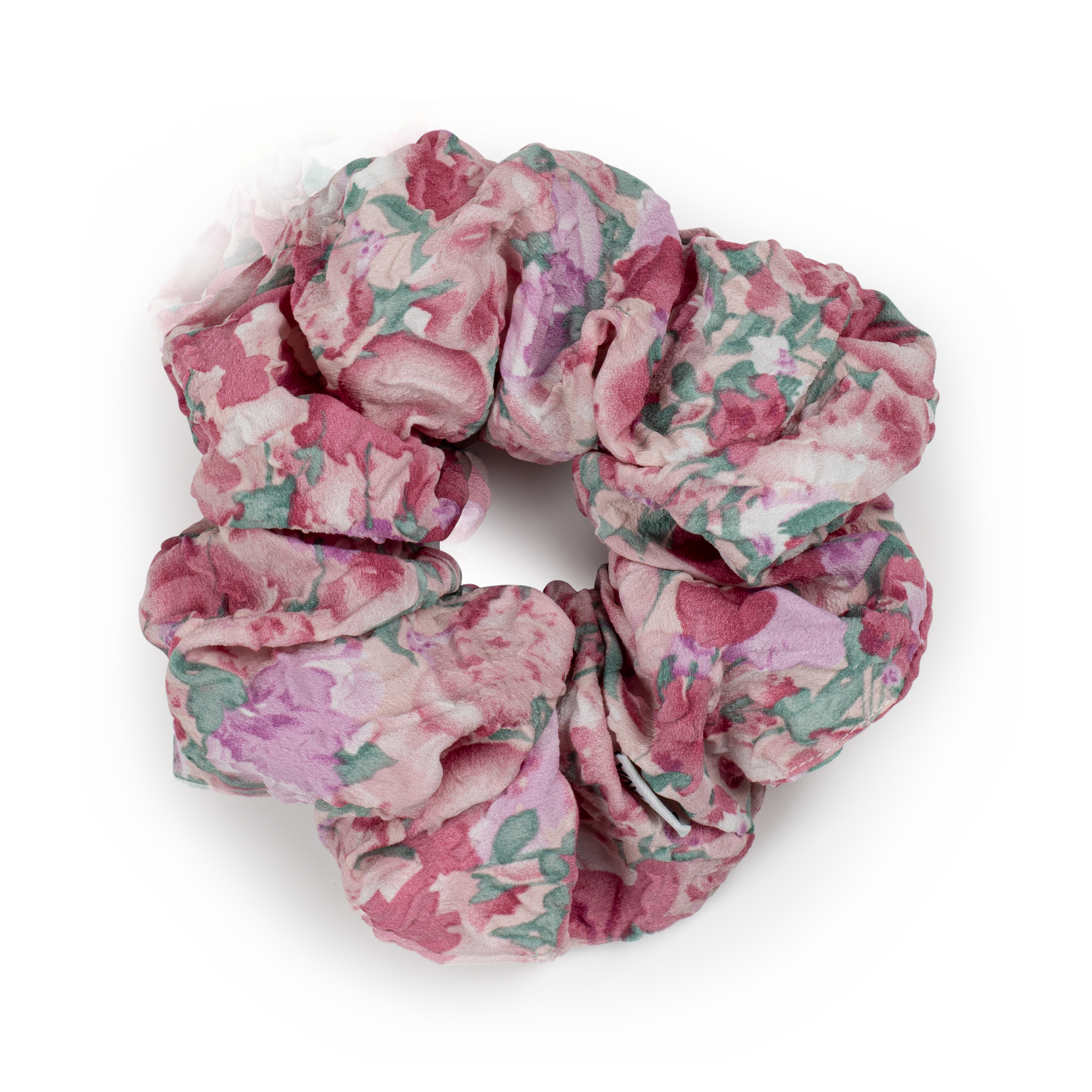 The Julie Wildflower Scrunchie in Rose Shadow by Sui Ava features a pink and green floral pattern with a ruffled texture, forming a charming vintage-inspired hair accessory against a white background.