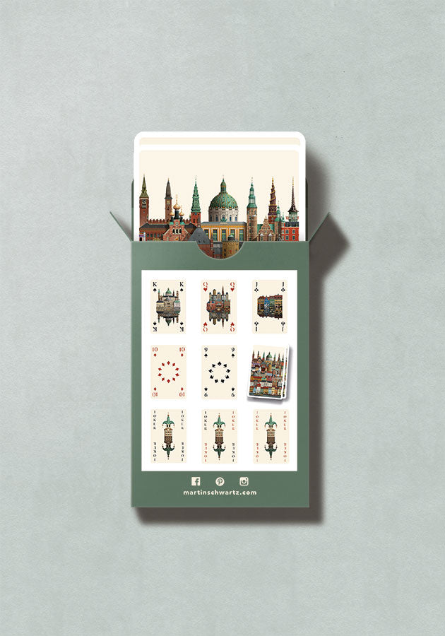 A green box of Playing Cards Copenhagen by Martin Schwartz—featuring illustrated playing cards showcasing architectural landmarks—makes a unique gift, with several cards partially visible inside the box and others displayed on the back, all set against a light gray background.
