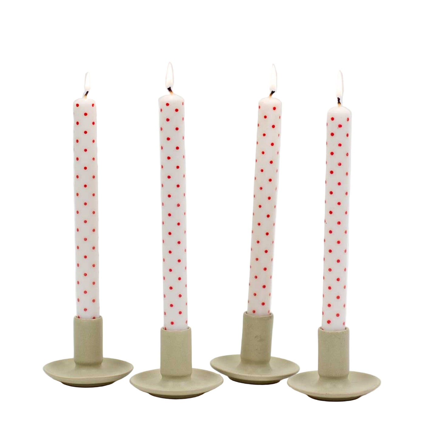 Four soy wax Dotted Candles in red from A World of Craft are lit and displayed in simple beige holders, arranged in a row.