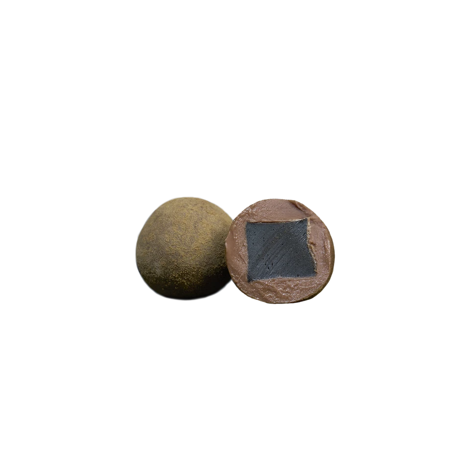 On a white background are two pieces of The Original Liqourice, Small, A by Lakrids by Bülow: one whole and brown, and the other cut in half to show its dark square-shaped liquorice center surrounded by a lighter milk chocolate outer layer.