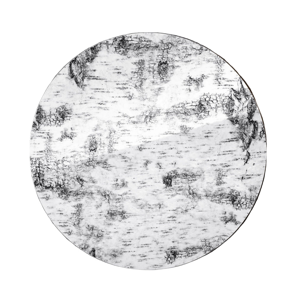 The Näver Pot Mat by Fine Little Day is a round birch bark piece with unique black and gray marbled patterns, adding style as a decorative accent or table protector.