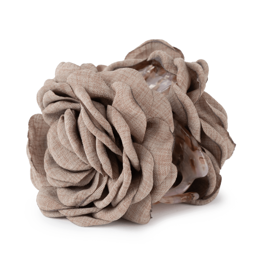 The Hair Claw Rosa in Taupe by Sui Ava features a taupe fabric flower with layered petals atop a polished spiral seashell, set against a plain white background—an elegant, strong-grip accessory for your hair.