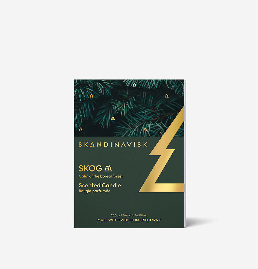 The Skandinavisk Seasonal Skog Gold Scented Candle 50h, 200g features a pine needle aroma, gold geometric design, and is labeled "Calm of the boreal forest." Made with Swedish rapeseed wax.