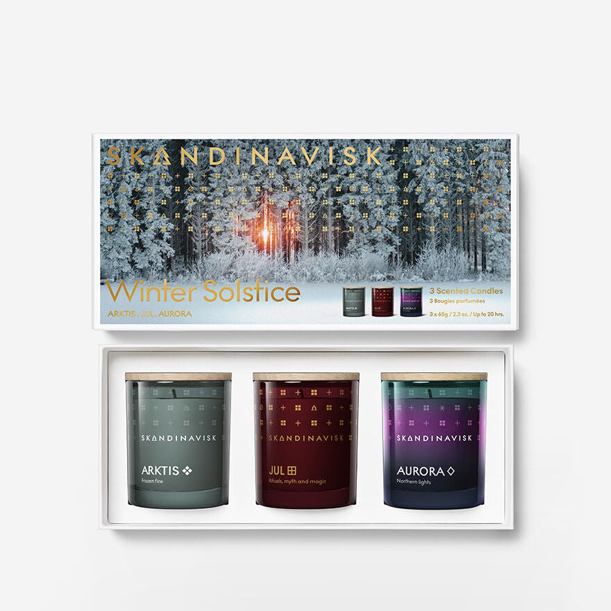 The Skandinavisk Scented Candle Winter Solstice Mini Giftset includes Arktis, Jul & Aurora candles made from Swedish rapeseed wax, arranged in a white tray with a snowy forest lid design.