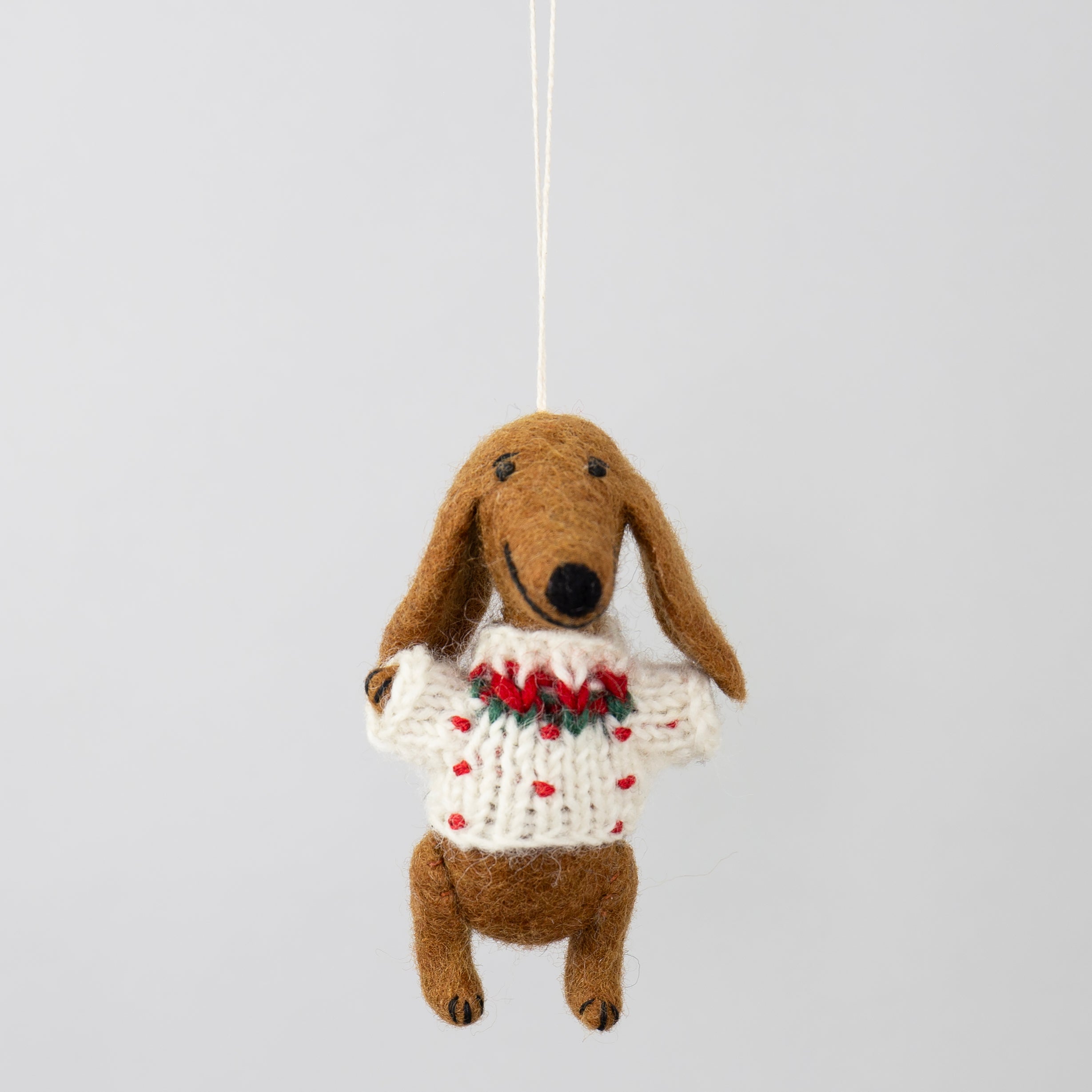 The Wool Dachshund w. Christmas Jumper Christmas Ornament by A World of Craft features a brown wool dachshund in a festive sweater with red and green accents, hanging by a string—perfect for your holiday décor.