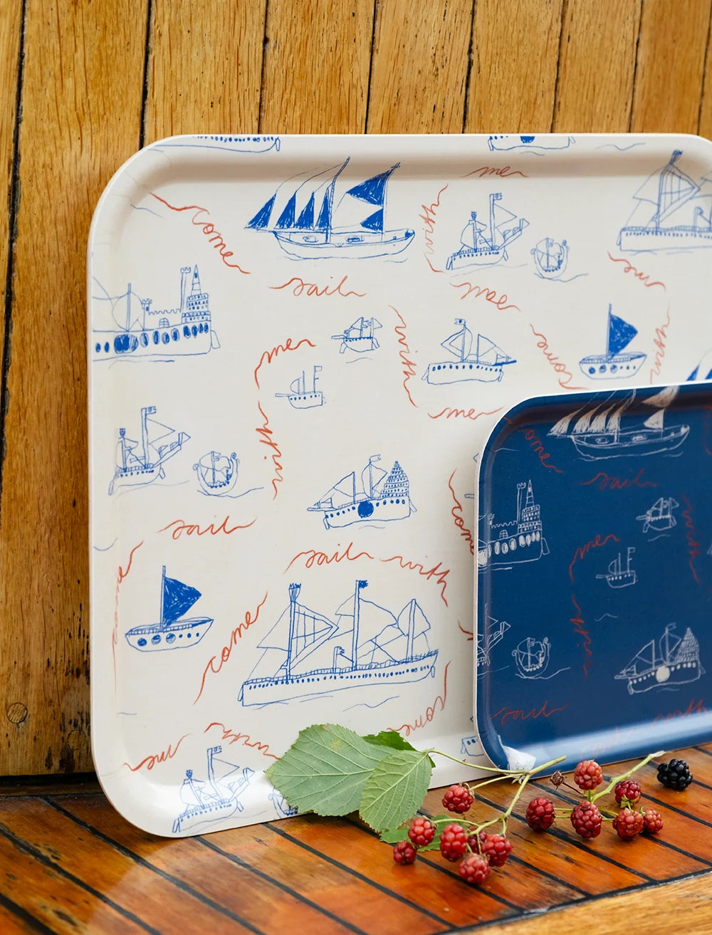 Fine Little Day's Ohoy Tray Small (27x20 cm) in birch wood features nautical sketches of ships, sailboats, and lighthouses in blue and cream tones. Raspberries and leaves are placed in front for a nostalgic touch.