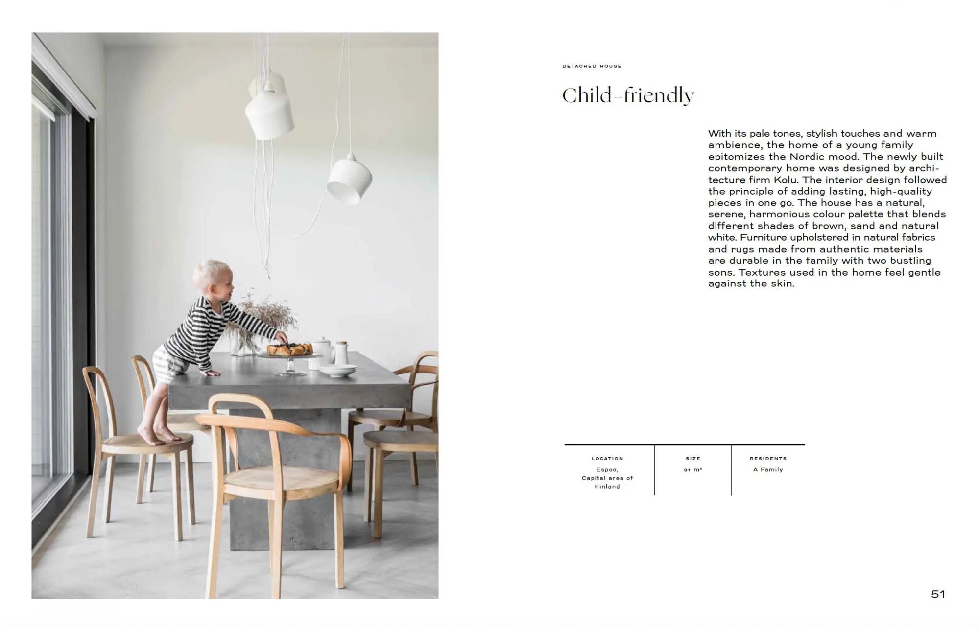 A young child in striped pajamas stands on a dining table set for breakfast, surrounded by wooden chairs and white pendant lights. This modern Finnish scene is featured in the "Nordic Interior Book" by Cozy Publishing.