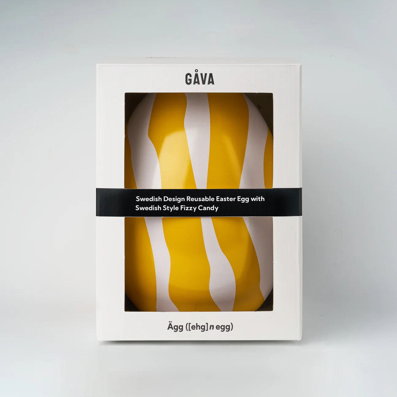 The Zebran Big Reusable Easter Egg by Gåva Gifting is a yellow and white striped Swedish-style tin Påskägg, packaged in a white GÅVA box with Swedish candy. “Ägg ([ehg], 1 egg)” is printed on the bottom.