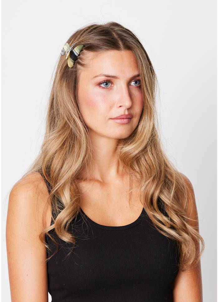 Woman wearing a small black and beige Sui Ava Helle Night Mini Hair Claw Clip at the side of her head.