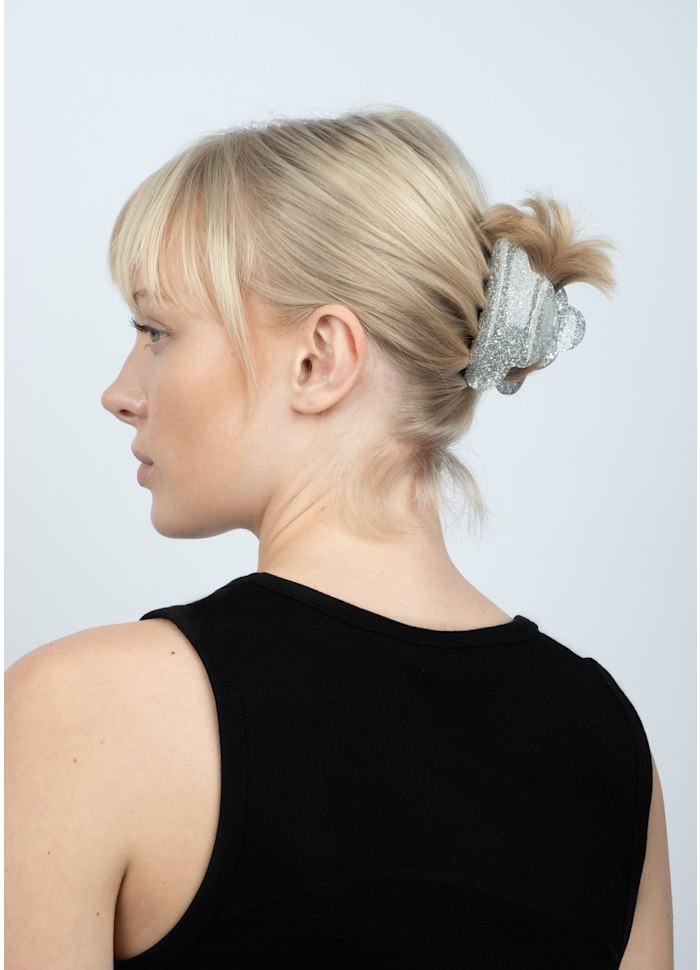Profile view of a person with blonde hair held in a silver glitter Sui Ava Lene Glitter Big Hair Claw Clip.