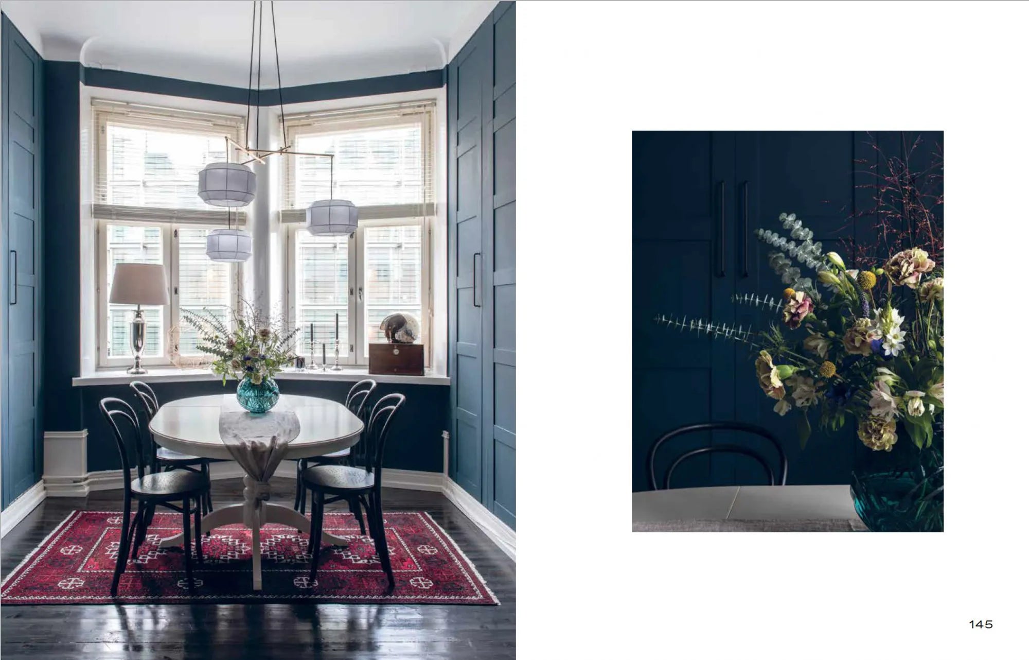 A dining room inspired by Nordic interior style features dark blue walls, a red patterned rug, a round white table with black chairs, and flowers—a scene captured in Cozy Publishing’s "Nordic Interior Book." On the right: a close-up of the table’s flowers.