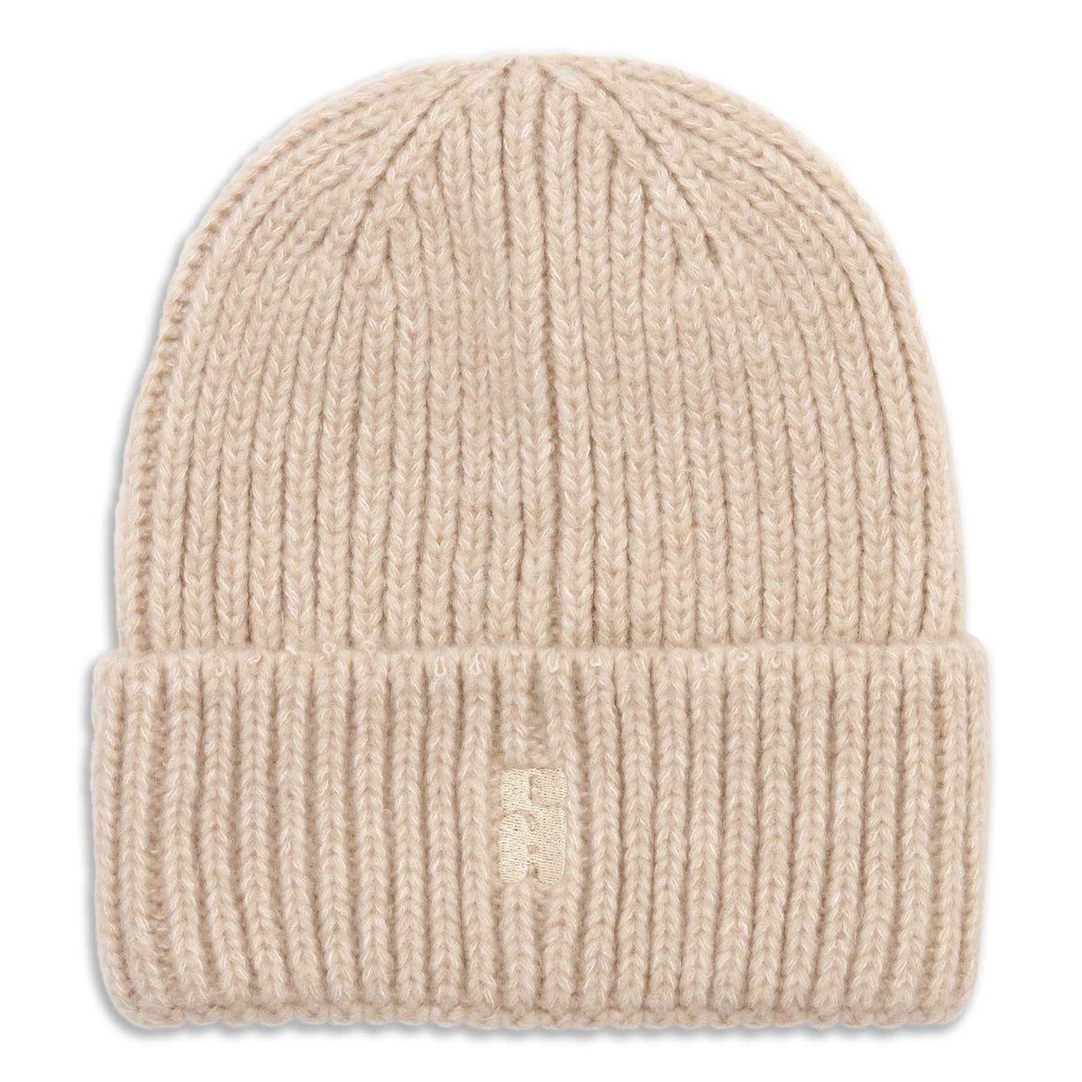 The Brenda Beanie in Beige from Sui Ava is a rib-knit, chunky beanie with a folded brim. Crafted from soft and cozy fabric, it features a small, subtle embroidered logo on the front of the brim and is photographed against a white background.
