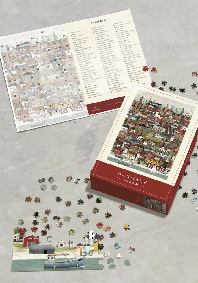 The Martin Schwartz Denmark Puzzle, 1000 Pieces, is partially assembled on a gray surface. The box and reference sheet display colorful Danish buildings, with loose pieces nearby—perfect for a fun family activity.