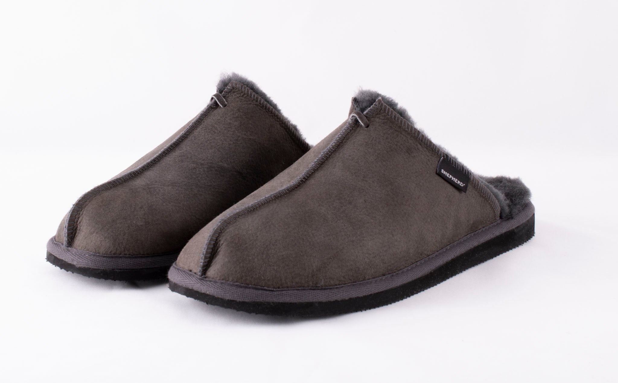 A pair of Shepherd of Sweden Hugo men's sheepskin slippers in Asphalt Grey with fleece lining and black soles, shown side by side on a plain white background.