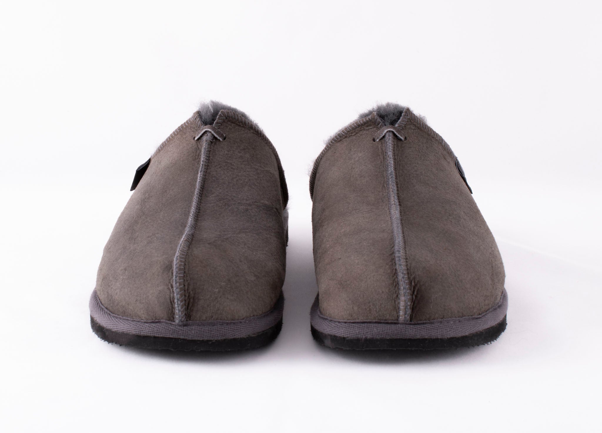 Shepherd of Sweden's Hugo men's sheepskin slippers in asphalt grey are shown facing forward with black soles on a plain white background.
